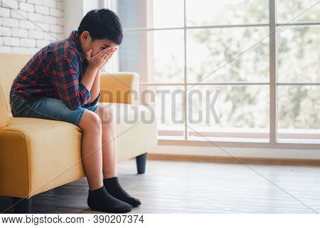 Young Asian Boy Sitting Alone On Sofa Feeling Sad And Depress. Bully In Child Or Sick Concept