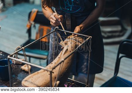 Close-up View Of Female Hands Gently Handling A Clay Whale In Workshop.