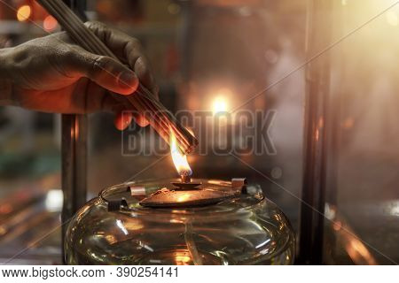 Close Up Hand Cense Joss Stick With Oil Lamp Fire. With Film Grain Effect