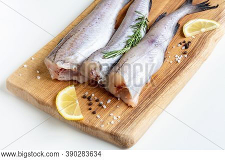 Raw Pollock Fish On A Wooden Board With Lemon And Spices