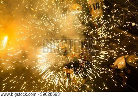 Fireworks are lit in the street near a crowd of people on New Year\\\'s Eve