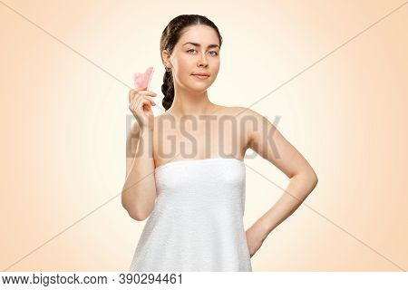 Gua Sha Massage. A Pretty Woman In A White Bath Towel Holds A Quartz Guasha Scraper In Her Hand. Bei