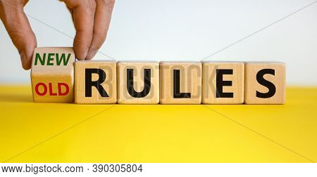 Male Hand Turns A Cube And Changes Words 'old Rules' To 'new Rules' On A Beautiful Yellow Table, Whi