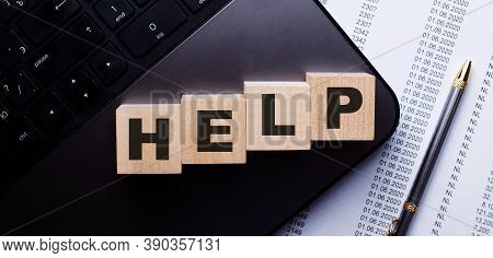 The Word Help Is Written In Red On Wooden Cubes On The Keyboard Next To The Pen.