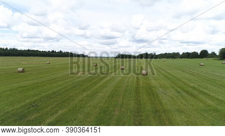 Big Hay Bale Rolls On A Green Field With Blue Sky And Clouds On The Background. Shot. Rural Landscap