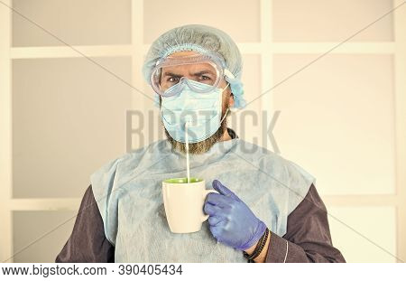 Man Wears Mask To Protect From Viral Infection. Man Drinks Coffee In Medical Mask. Morning At Home O