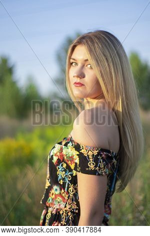 Overlight Bright Portrait Of A Charming Attractive Blonde In Flowery Dress In The Field