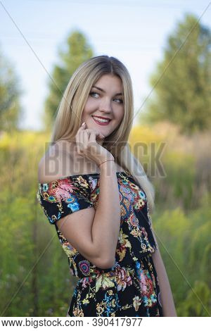 Overlight Bright Portrait Of A Charming Attractive Blonde In Flowery Dress In The Field