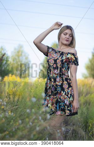 Overlight Bright Portrait Of A Charming Attractive Blonde In Flowery Dress In The Field
