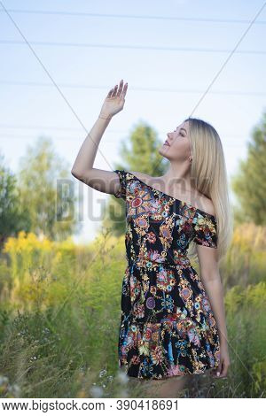Overlight Bright Portrait Of A Charming Attractive Blonde In Flowery Dress In The Field