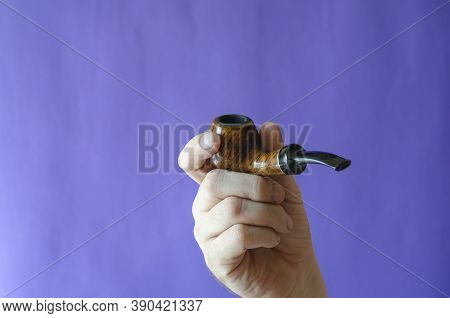 Briar Root Smoking Pipe In Hand. A Man's Hand Holds A Classic Smoking Pipe On A Blue Background. Sel