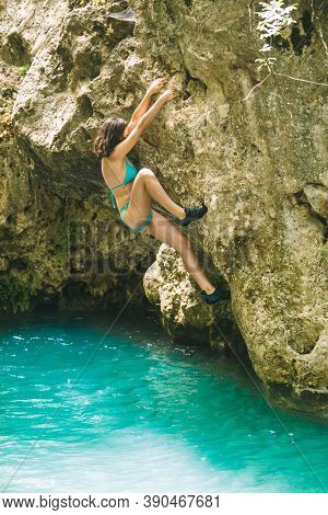 A Woman In A Swimsuit Climbs A Cliff Above The Water, Climbing Over A Mountain River, Bouldering In 