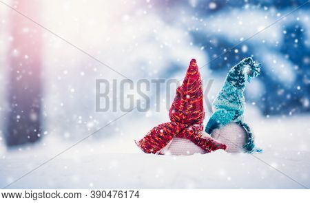 Little Snowmans On Soft Snow On Blue Background In Snowfall