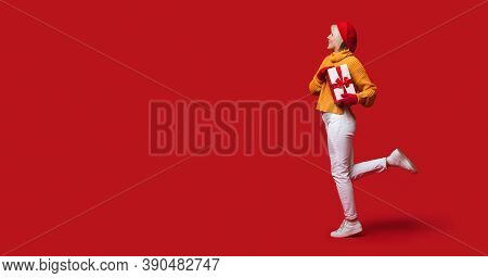 Lovely Woman With Hat And Red Gloves Is Posing On A Wall With Free Space Holding A Present Box And S