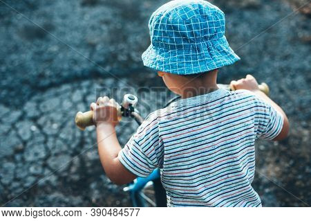 Upper View Photo Of A Caucasian Boy Riding The Bike And Wear A Hat In A Summer Day