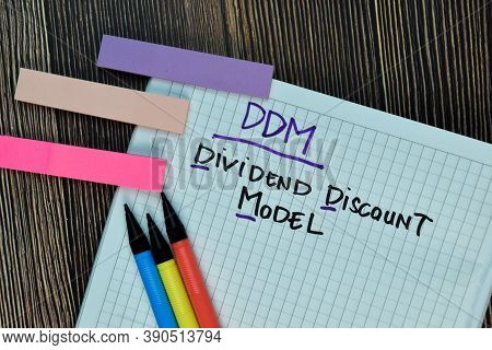 Ddm - Dividend Discount Model Write On A Book Isolated On Wooden Table.