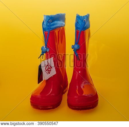 Childrens Red Rubber Boots With A Cuff. Wet Rainy Weather Isolated On Yellow Background.