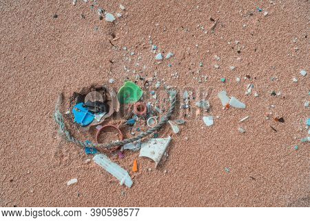 Plastic pollution on shore of beach. Ocean microplastic marine debris.