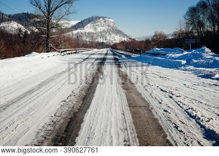 Tire Tracks In The Snow, Winter Road, Empty Road In Winter Goes Far To The Horizon, Covered With Sno