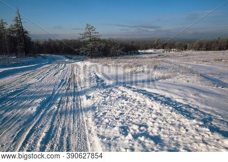 Tire Tracks In The Snow, Winter Road, Empty Road In Winter Goes Far To The Horizon, Covered With Sno