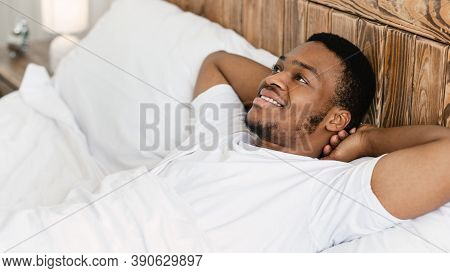 Happy Wellslept African American Guy Lying Awake In Bed In The Morning In Bedroom At Home. Good Morn