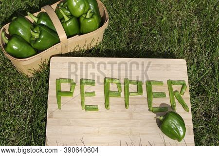 Ripe Green Peppers With Word Pepper In Pieces On Grass