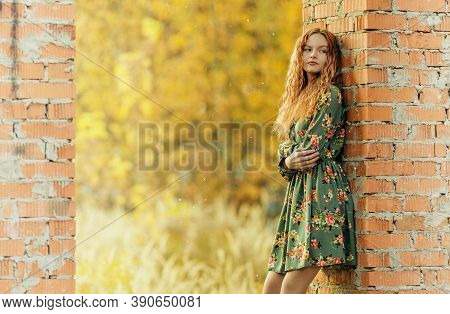 Teen Girl In Dress Standing Near A Brickwork In Abandoned Place. Shallow Dof