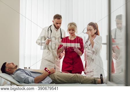 Training With Interns. A Young Blonde Doctor Gives A Lecture To Interns In The Office, Discussing Th