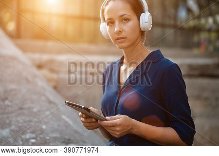 Pretty Woman Holding Tablet And Wearing Headset. Study While Travel Idea. Studentship And Distance L