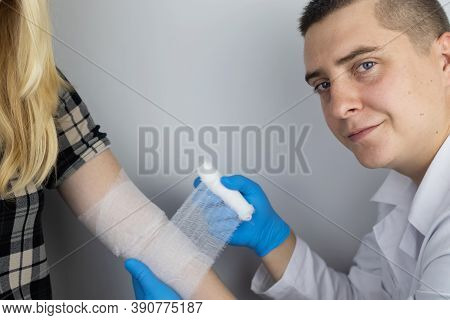 The Traumatologist Puts A Bandage On The Elbow Of The Female Patient. The Concept Of Help With Fract