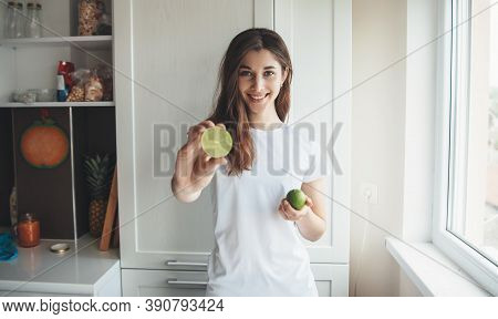 Lovely Caucasian Woman In Casual Clothes Posing In The Ktichen Is Showing At Camera A Sliced Lemon