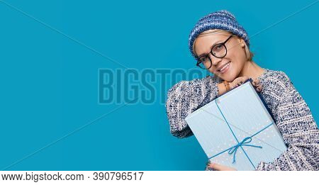 Close Up Photo Of A Caucasian Woman With Glasses And Hat Posing With A Gift Near Blue Studio Free Sp