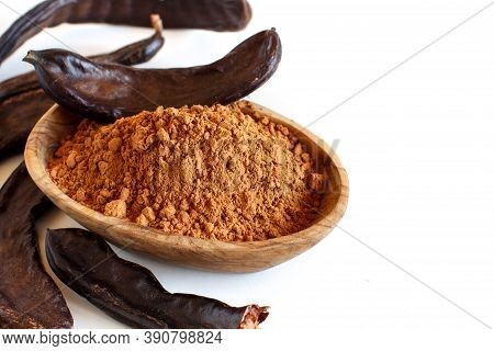 Dry Carob Flour And Pods In A Wooden Bowl Close Up Isolated On White