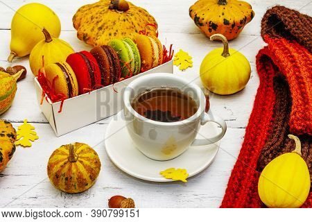 French Macarons In Autumn Colors With Cup Of Hot Tea