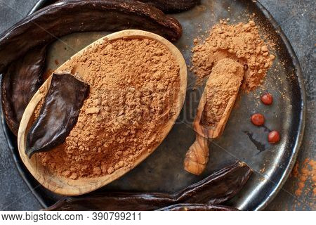 Dry Carob Powder And Pods Top View On A Grey Table