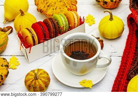 French Macarons In Autumn Colors With Cup Of Hot Tea
