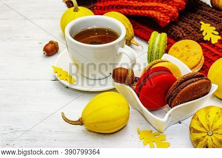 French Macarons In Autumn Colors With Cup Of Hot Tea