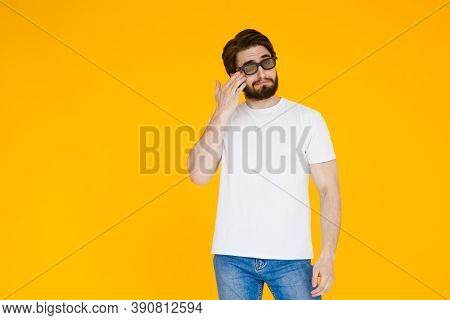Young Bearded Man In A White T Shirt With 3d Glasses Watch A Movie Melodrama On A Yellow Background.
