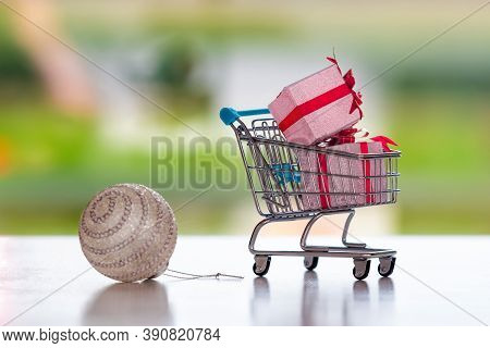 Christmas Ball And Shopping Cart With Presents On Blurred Background,  Christmas Shopping Concept, C