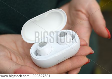 Young Girl Holds White Wireless Firo Vacuum Earbuds. Firo Is Wireless Technologies European Brand