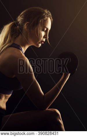 Slim Athletic Woman Holding Dumbbell In The Hand On Black