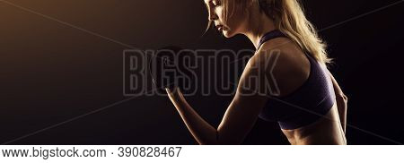 Slim Athletic Woman Holding Dumbbell In The Hand On Black
