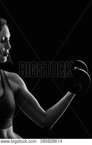 Slim Athletic Woman Holding Dumbbell In The Hand On Black