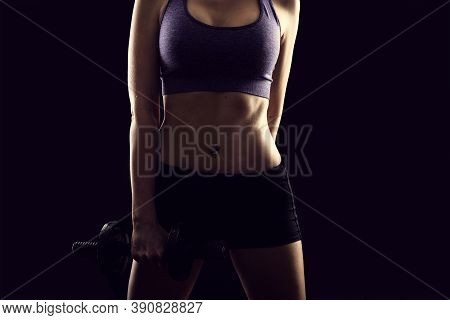 Slim Athletic Woman Holding Dumbbell In The Hand On Black