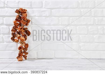 Dried red bell pepper hanging on white brick wall textured background 
