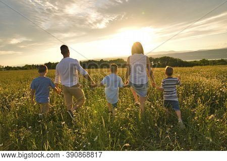 Happy Family On Daisy Field At The Sunset Having Great Time Together Walking Field