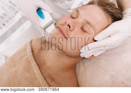 Close Up Of An Attractive Man Getting Facial Skincare Treatment By Cosmetologist. Beautician Using U
