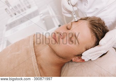 Handsome Relaxed Man Getting Skin Tightening Treatment At Beauty Salon