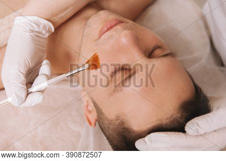 Close Up Of A Young Handsome Man Having Face Mask Applied By Professional Beautician