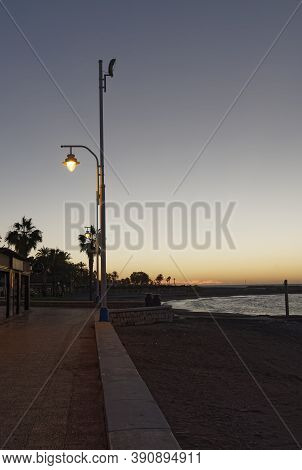 View Of The Sea And Lamppost On The Pedregalejo Beach At Dusk.